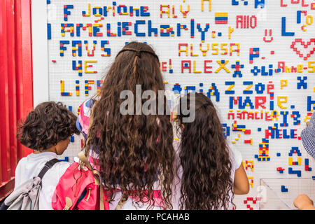 Close-up details of children playing along the wall full of names made from colorful puzzle blocks. Colorful abstract puzzle and letter details Stock Photo