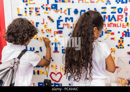 Close-up details of children playing along the wall full of names made from colorful puzzle blocks. Colorful abstract puzzle and letter details Stock Photo