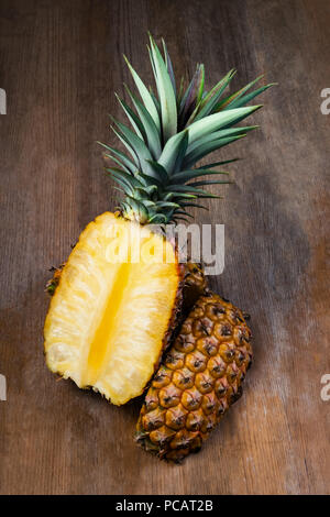 Pineapple fruit cut half displayed on wooden background. Juicy organically grown ripe and sweet Stock Photo