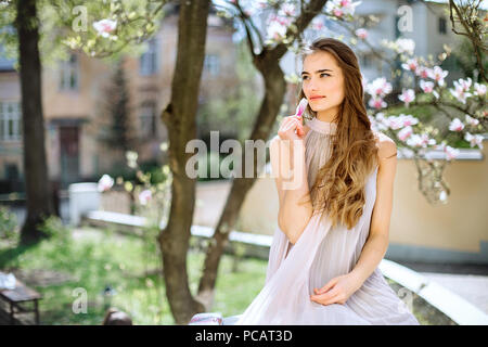 Beautiful young girl stands among the flowering trees. White flowers. Spring Girl with her hair in a beige dress. Portrait. Romance Stock Photo