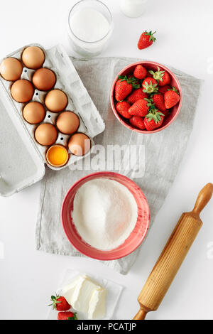 Bakery background. Recipe for strawberry pie. Rustic style. Ingredients for cooking strawberry pie or cake on white table. Flat lay, top view. Eggs, f Stock Photo