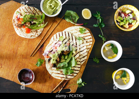 Dinner table with tacos grill with vegetable salsa, guacamole sauce, chicken and lemonade top view Stock Photo