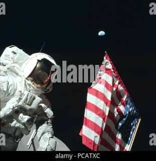 Astronaut Harrison Schmitt poses on the Lunar surface next to an American flag during Apollo 17. (moon surface seen on bottom of image) Stock Photo