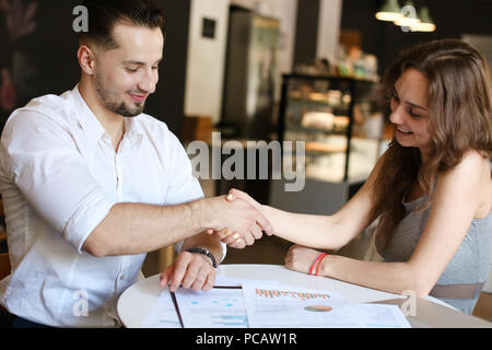 Caucasian businessman and woman working with documents, shaking hands. Stock Photo