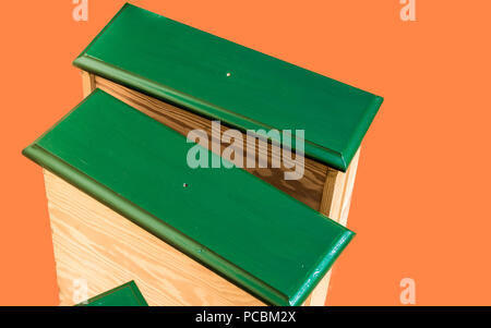 Renovated, green painted and repaired drawers of an old ugly used cupboard, ready for recycling, released in front of an orange background, furniture  Stock Photo