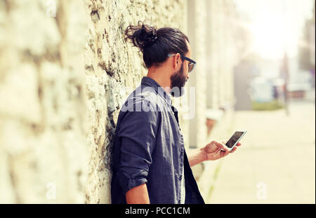 close up of man with smartphone at stone wall Stock Photo