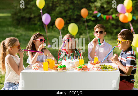 happy kids blowing party horns at summer birthday Stock Photo