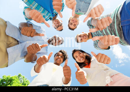 happy friends showing thumbs up standing in circle Stock Photo
