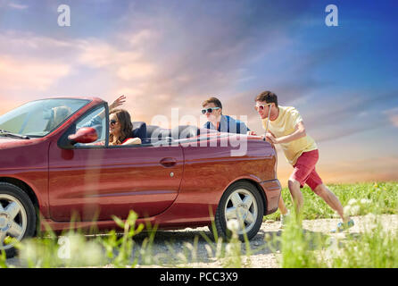 friends pushing broken convertible car Stock Photo