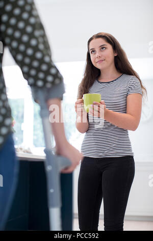 Teenage Daughter Making Drink For Disabled Parent Stock Photo