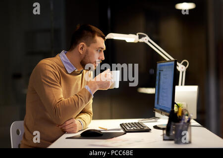 man drinking coffee and working on code at office Stock Photo