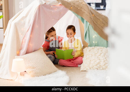 little girls reading book in kids tent at home Stock Photo