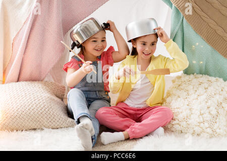 girls with kitchenware playing in tent at home Stock Photo