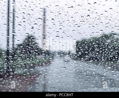Raindrops falling on glass, abstract blurs - monsoon stock image . Stock Photo