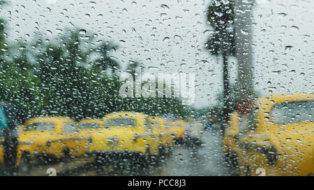 Raindrops falling on glass, abstract blurs - monsoon stock image of traditional yellow taxi of Kolkata ,West Bengal, India Stock Photo
