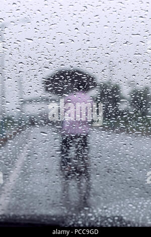 Raindrops falling on glass, abstract blurs - monsoon stock image . Stock Photo