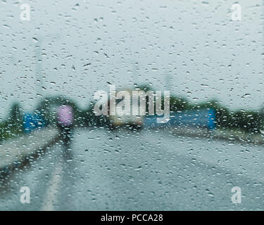 Raindrops falling on glass, abstract blurs - monsoon stock image . Stock Photo