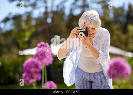 senior woman with camera photographing flowers Stock Photo