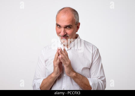 Cunning tricky mature man thinking looking in side with hand together over white background. Stock Photo