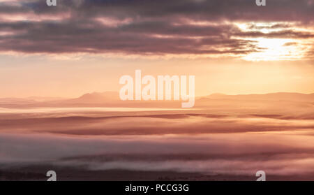 Mountain silhouettes and low morning clouds at sunrise Stock Photo