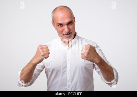 Closeup portrait happy successful hispanic man winning, fists pumped celebrating success isolated grey wall background. Stock Photo