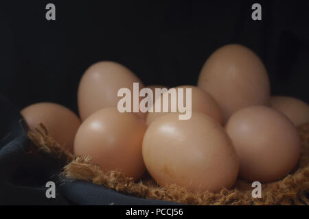 Eggs in a nest on hemp sack, dark corner. Stock Photo