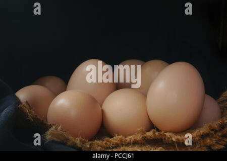 Eggs in a nest on hemp sack, dark corner. Stock Photo