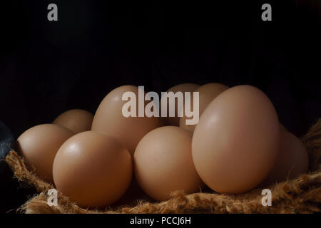 Eggs in a nest on hemp sack, dark corner. Stock Photo