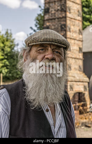 Portrait, front view close up of old traditional UK canal boat man in tweed flat cap with long grey beard, isolated outdoors, Black Country Museum, UK. Stock Photo