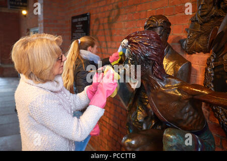 Sue Stopps (white coat), wife of David Stopps (not pictured), attempts to clean the statue of David Bowie in Aylesbury after it was vandalised days after being unveiled Stock Photo