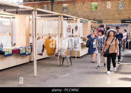 People shopping and walking around the stalls in Old Spitalfields indoor market. Spitalfields, East London, UK Stock Photo