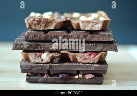 A gift pack of artisan handmade chocolate. Chocolate bars with dried fruit on dark background, front close up view. Stock Photo