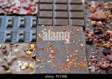 A gift pack of artisan handmade chocolate. Chocolate bars with dried fruit on dark background, front close up view. Stock Photo