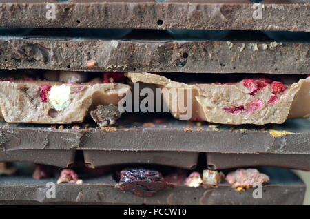 A gift pack of artisan handmade chocolate. Chocolate bars with dried fruit on dark background, front close up view. Stock Photo