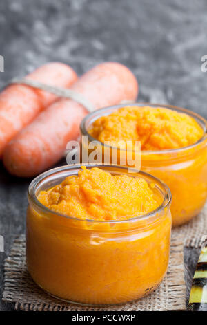 Carrot  puree in glass jars on wooden table Stock Photo
