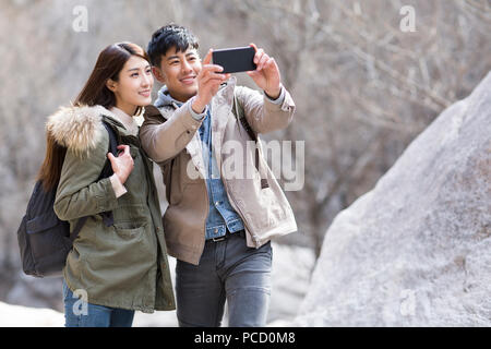 Happy young Chinese couple taking selfies outdoors in winter Stock Photo