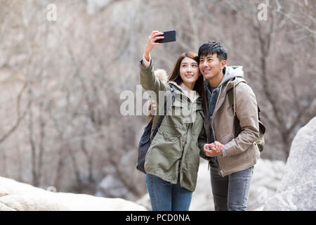 Happy young Chinese couple taking selfies outdoors in winter Stock Photo