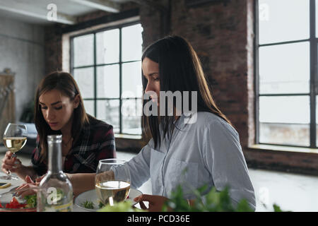 Two girlfriends have dinner and drinking wine in the home kitchen Stock Photo