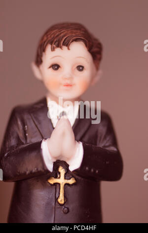 Cake topper Catholic holy communion ceremony religious boy praying to Christian God in church. Stock Photo