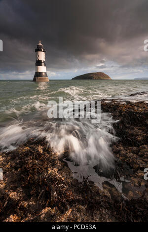 Lighthouse at Penmon Point under clouds, Anglesey, North Wales with Puffin Island in the background Stock Photo