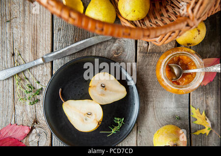 Autumn harvest concept - cut fresh ripe pear on the black plate and group of yellow pears in the basket and on the rustic wooden table, Vegetarian, ve Stock Photo