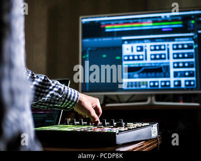 close up man's hand recording sound in recording music studio using new modern equipment with large monitor and laptop Stock Photo