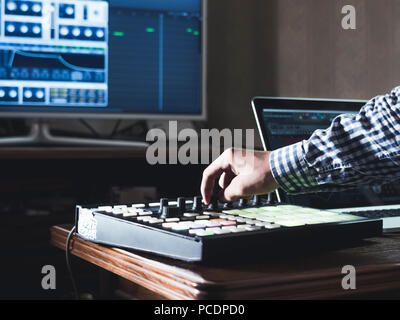 close up man's hand recording sound in recording music studio using new modern equipment with large monitor and laptop Stock Photo