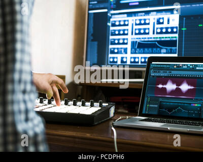 close up man's hand recording sound in recording music studio using new modern equipment with large monitor and laptop Stock Photo