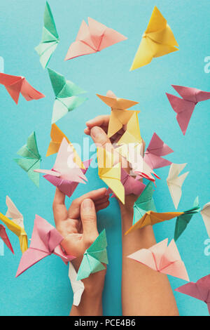 Mental health concept. Colorful paper butterflies flying and sitting on womans hands. Harmony emotion. Origami. Paper cut style. Toned Stock Photo