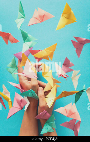 Mental health concept. Colorful paper butterflies flying and sitting on womans hands. Harmony emotion. Origami. Paper cut style. Toned Stock Photo