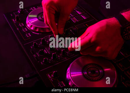Dj mixing on turntables with color light effects. Soft focus on hand. Close-up. Fun, youth, entertainment and fest concept Stock Photo