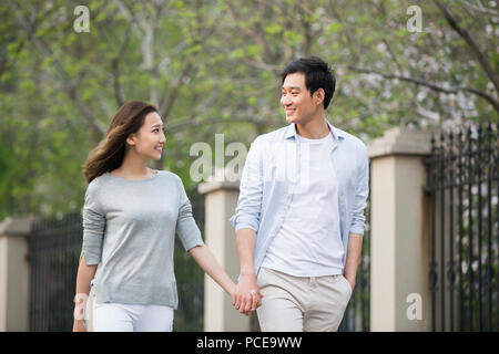 Happy young Chinese couple holding hands walking Stock Photo