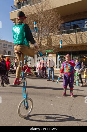 ASHEVILLE, NORTH CAROLINA, USA - FEBRUARY 7, 2016: Colorful jugglers, one on a unicycle, swap juggling pins back and forth between them to entertains  Stock Photo