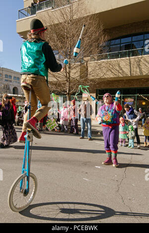 ASHEVILLE, NORTH CAROLINA, USA - FEBRUARY 7, 2016: Colorful jugglers, one on a unicycle, swap juggling pins back and forth between them to entertains  Stock Photo